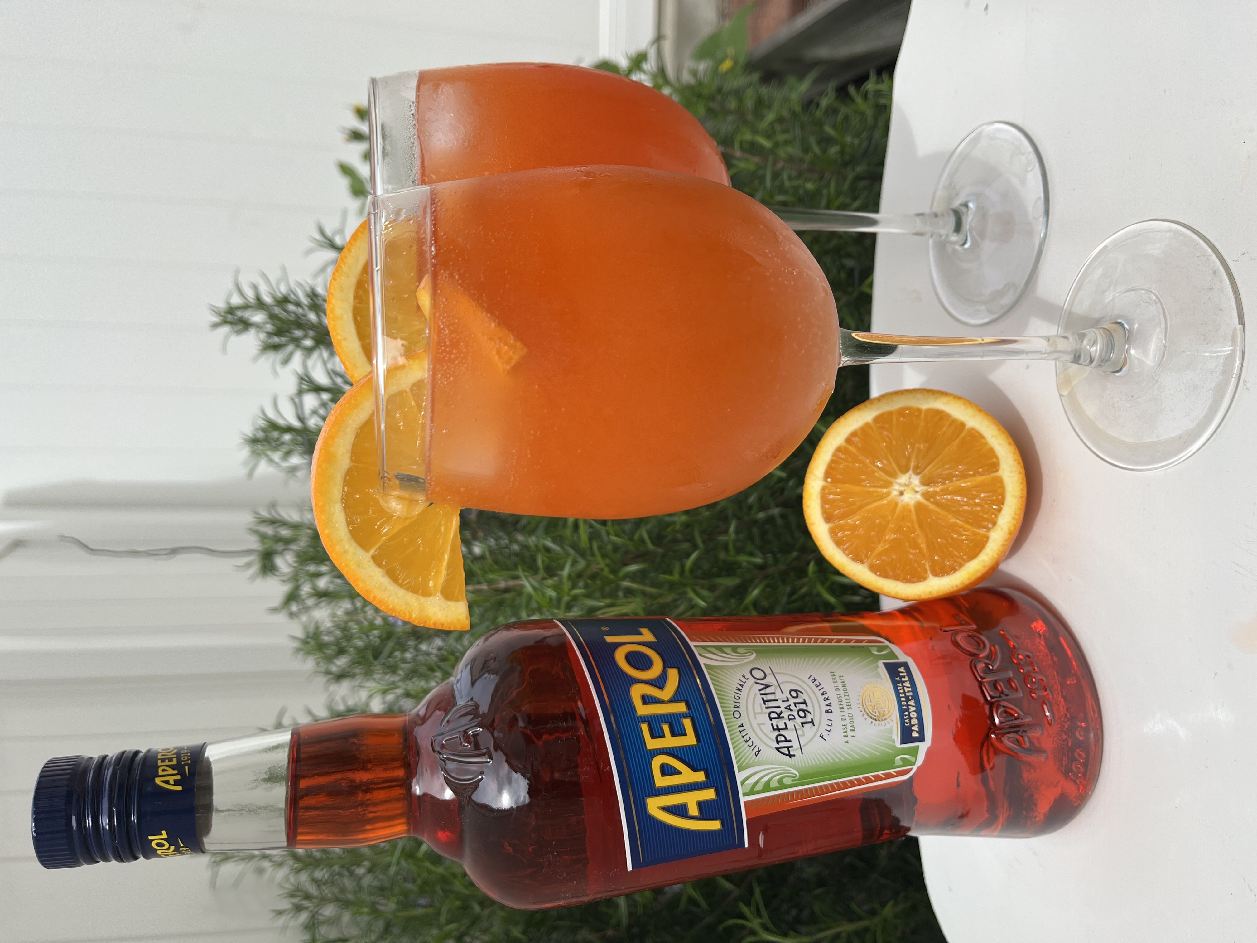 Two glasses of Aperol Spritz next to a Aperol and Champagne bottle.